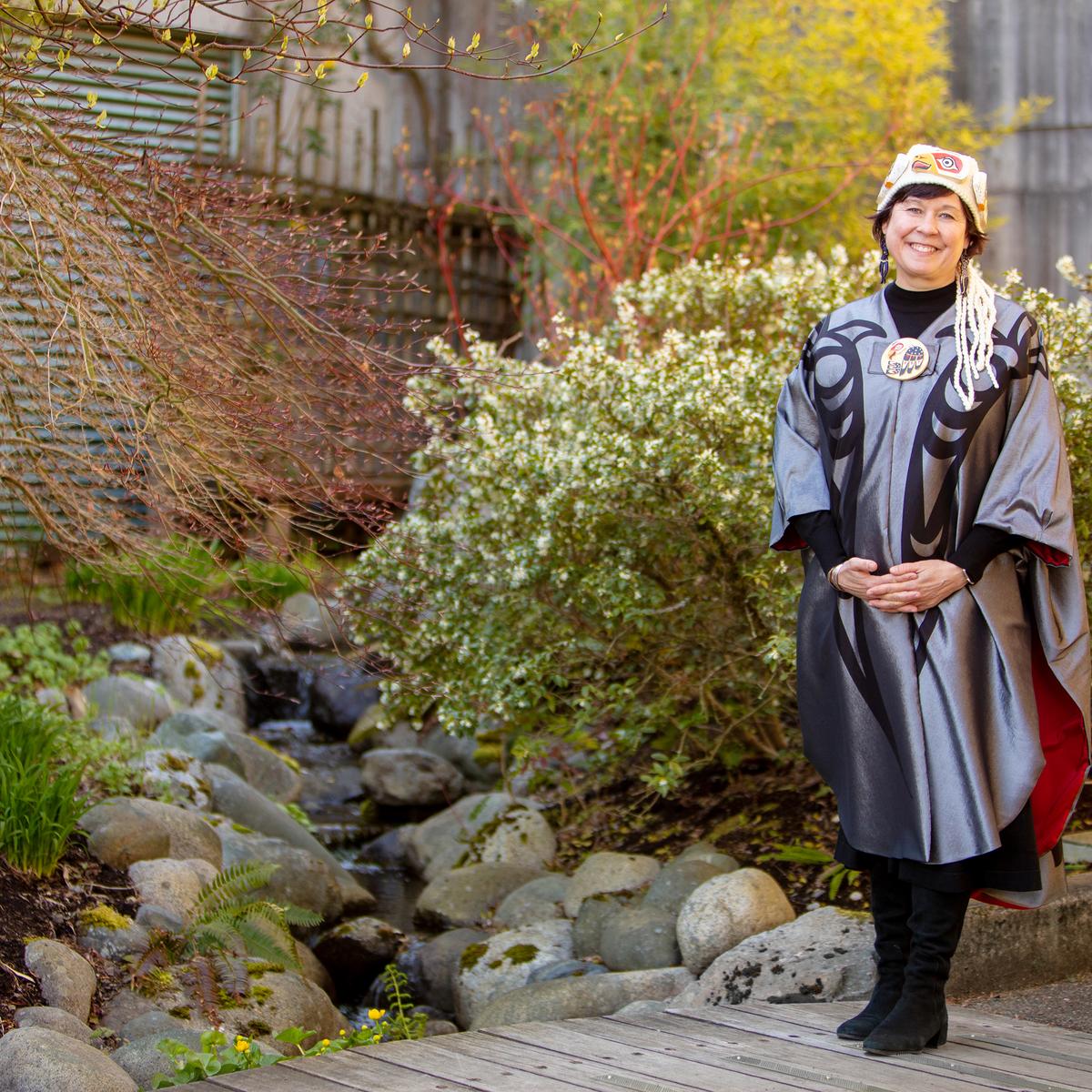 Deborah Saucier wears her convocation regalia and poses in the gardens at VIU's Nanaimo campus