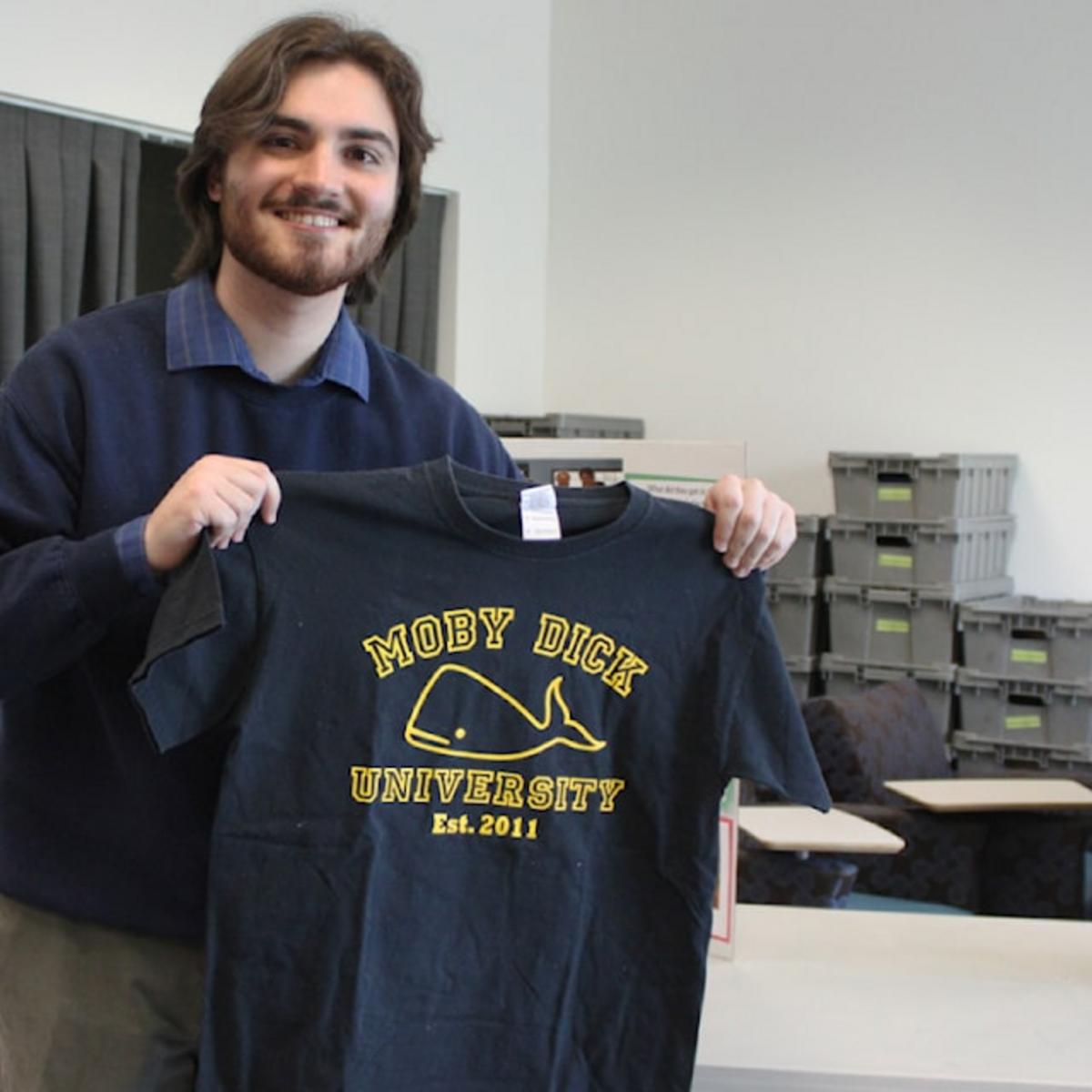 A student holds up a sweater that reads Moby Dick University