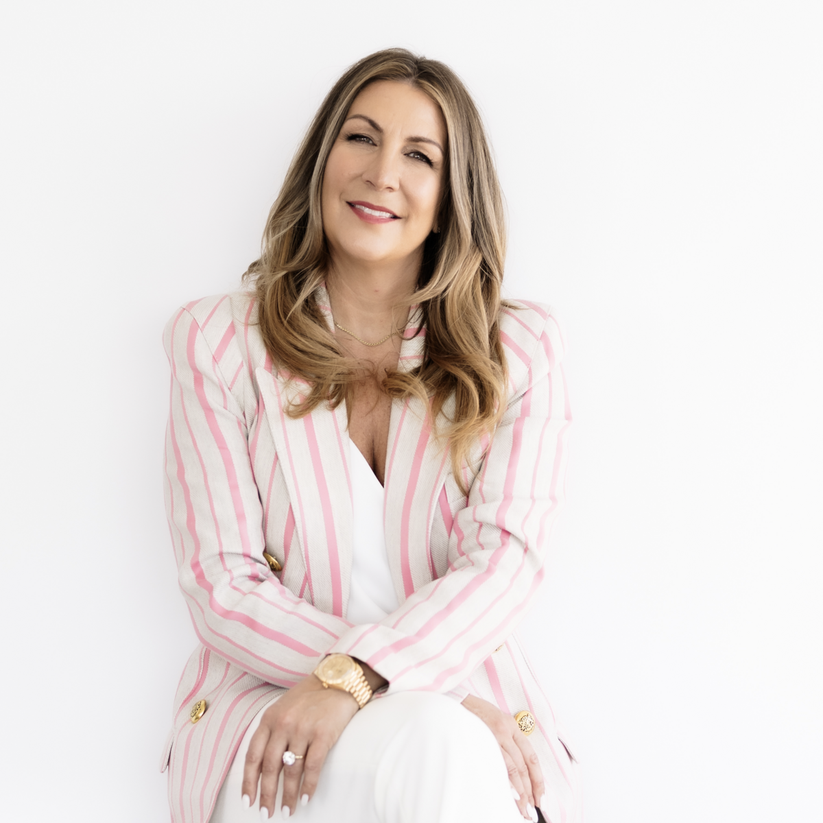 Jane Stoller sitting down against a white backdrop and smiling at the camera.