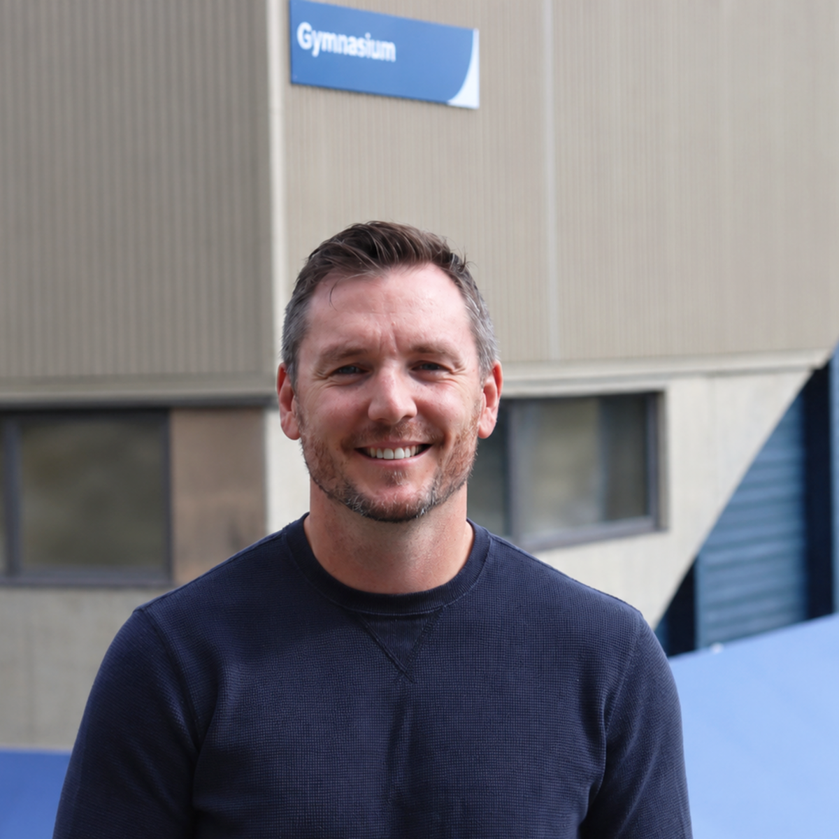 Jordan Herbison standing outside the VIU gym in a sunny day and smiling.