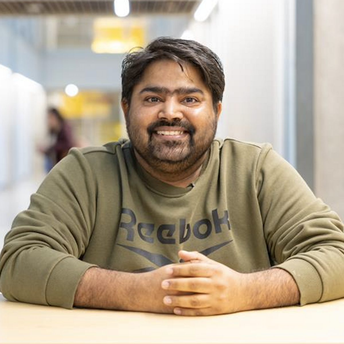 Lavdeep sitting at a table and smiling at the camera.