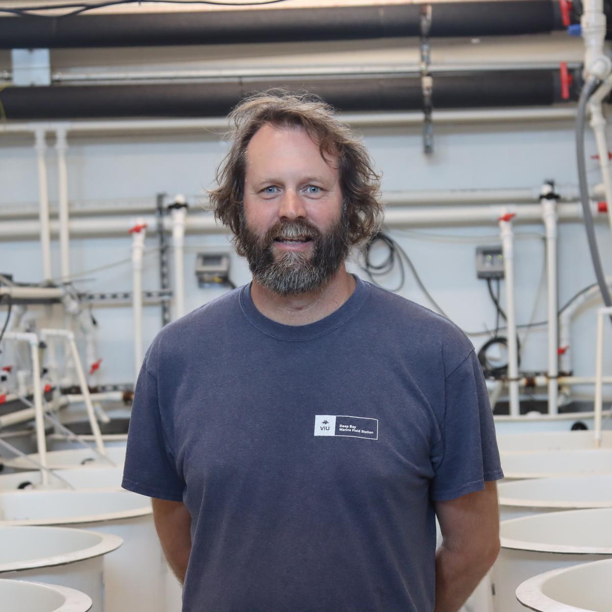 Tim Green standing in the tank room and looking at the camera at VIU Deep Bay Station