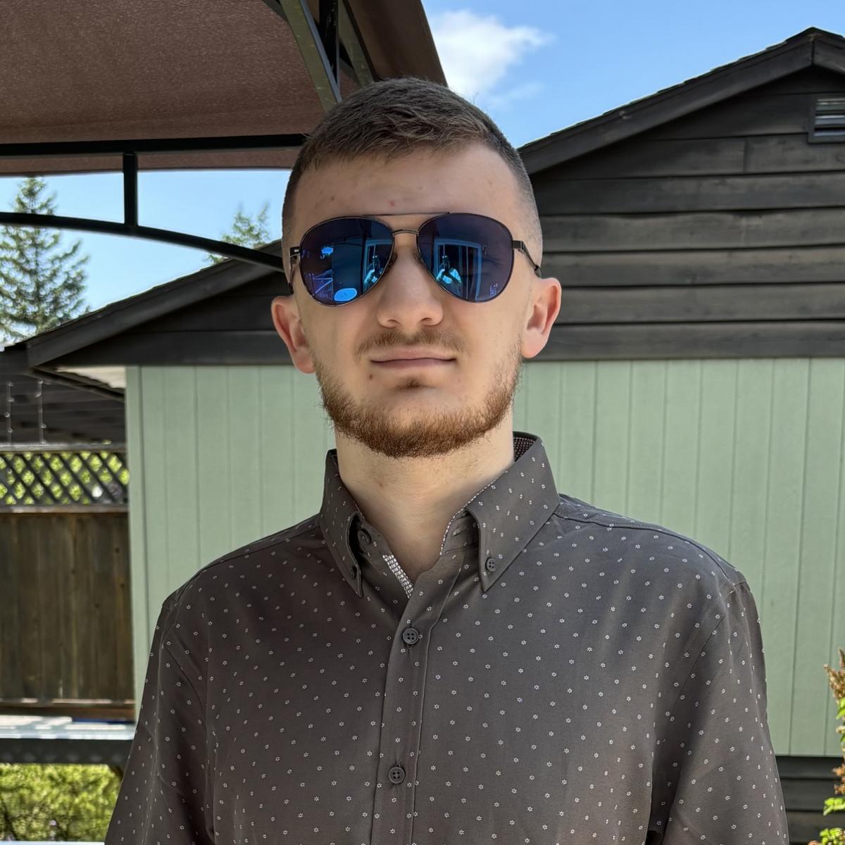 Zackary Sutton outside wearng sunglasses and looking at the camera