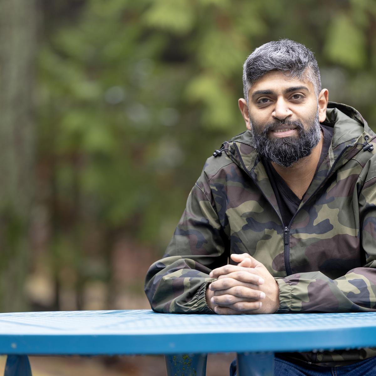 Harold Chandra sits at a blue table outside