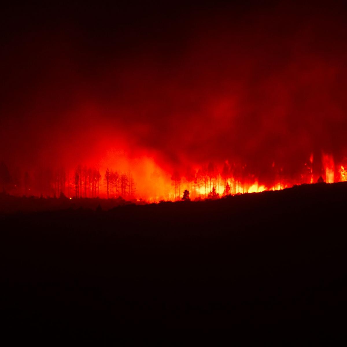 A wildfire burns over a ridge at night