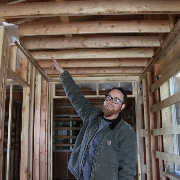 Program Instructor Andrew McLeod points to some of the work students have done inside the home