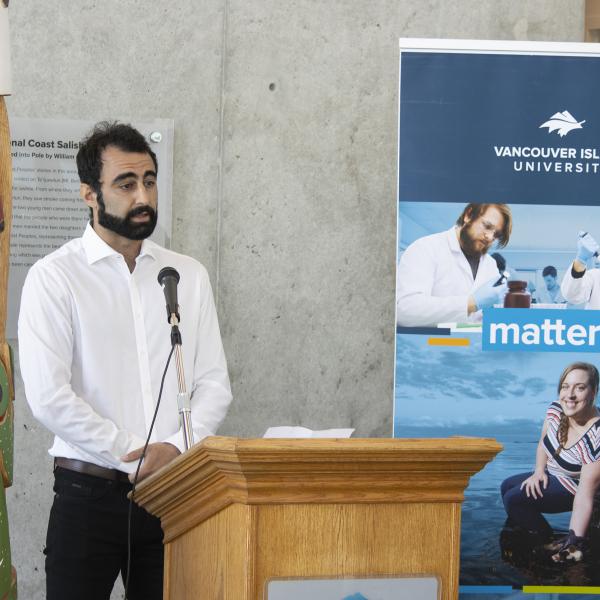 Armin Saatchi, a VIU graduate student, stands at a podium during the BC government funding announcement.