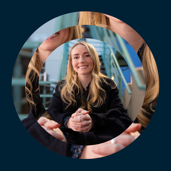 A student sits with her hands clasped in front of her