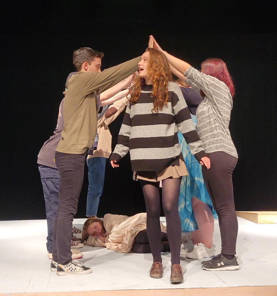 An actor walks under the hands of other actors while rehearsing on the Malaspina Theatre stage.
