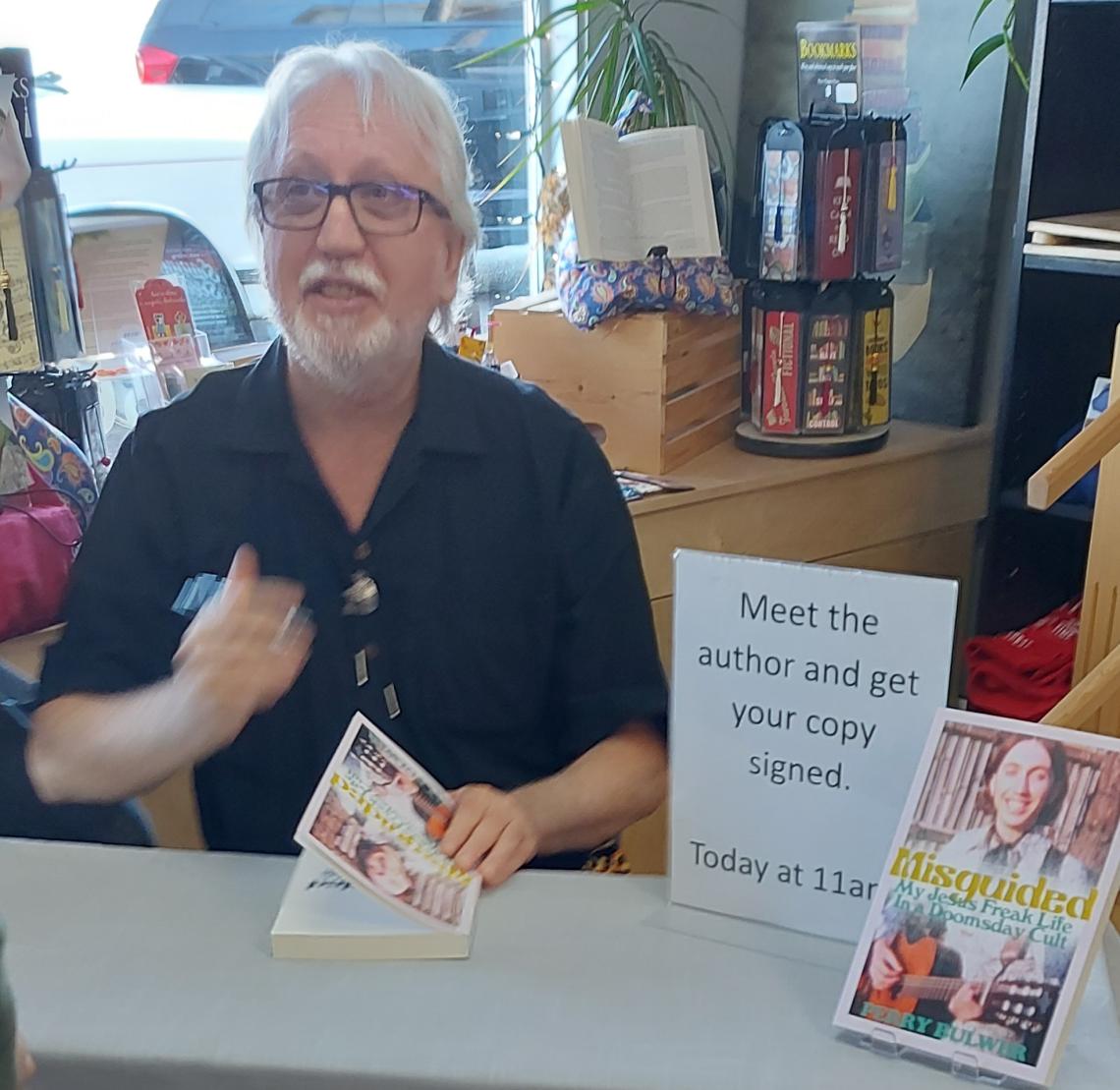 Perry sits at a table with copies of his book