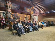 A group of students sits in a longhouse