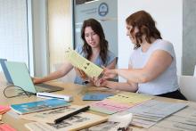 VIU Research Assistants Elise Cullon and Katie Carroll. Katie shows Elise a document.