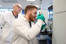 Dr. Chris Gill observes as Lucas Abruzzi puts a sample in the mass spectrometer.