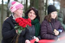 Woman holds roses standing next to two other women