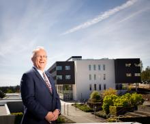Ralph Nilson, former VIU president, smiles with the Dr. Ralph Nilson Centre for Health and Science in the background