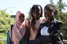 Facing the camera and standing from left to right are refugee students Hanan Ali Abdi, Nyagua Deng Goch, and Daniella (Sifa) Mukenge