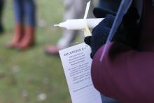 Someone holds a white candle with a tag that reads December 6th, National Day of Remembrance and Action on Violence Against Women