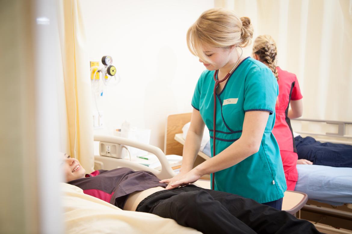 A nursing student practices on another nursing student