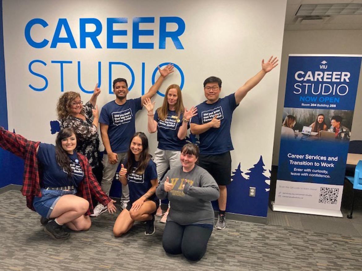 A group poses with the Career Studio sign and banner