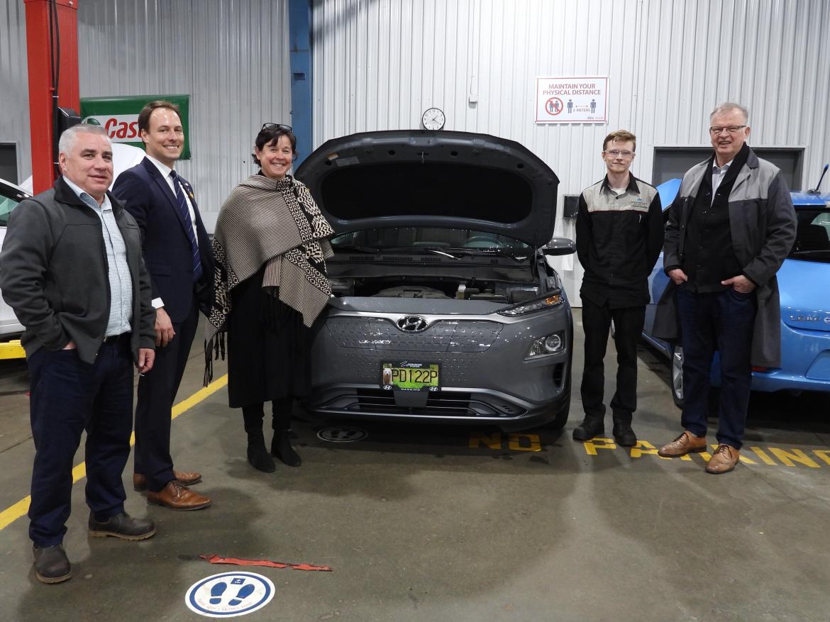 Five people pose around an electric vehicle