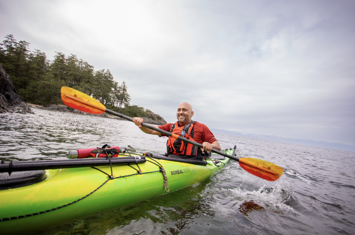 Farhad Moghimefar paddling a kayak and smiling off into the distance