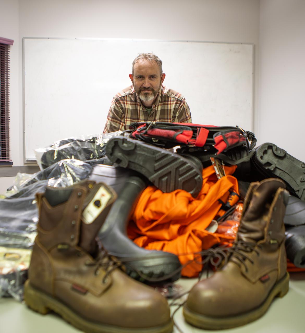 Mike with boots, waterproof jackets and waders laid out on a table