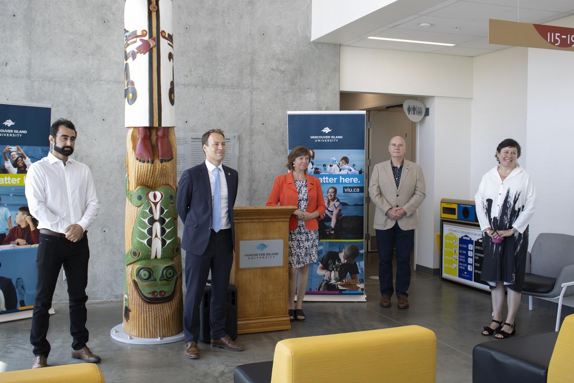 Five people stand in VIU's Health and Science Centre during a media conference.