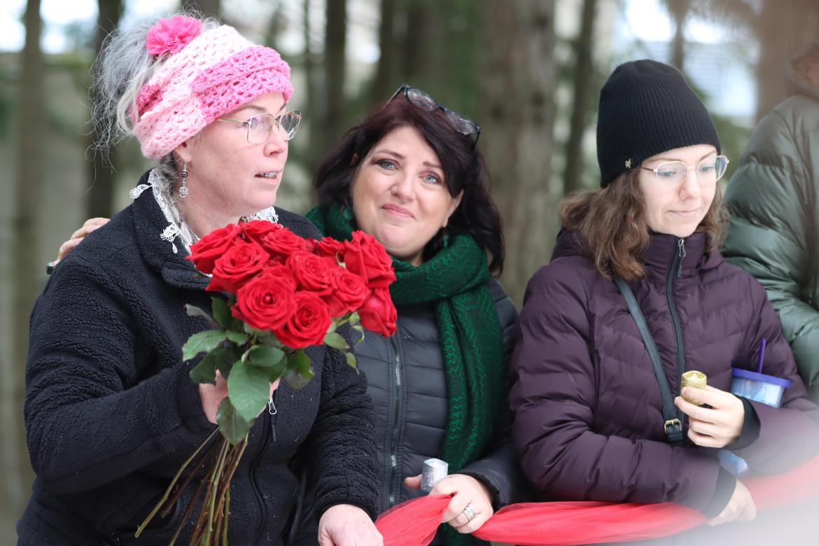 Woman holds roses standing next to two other women