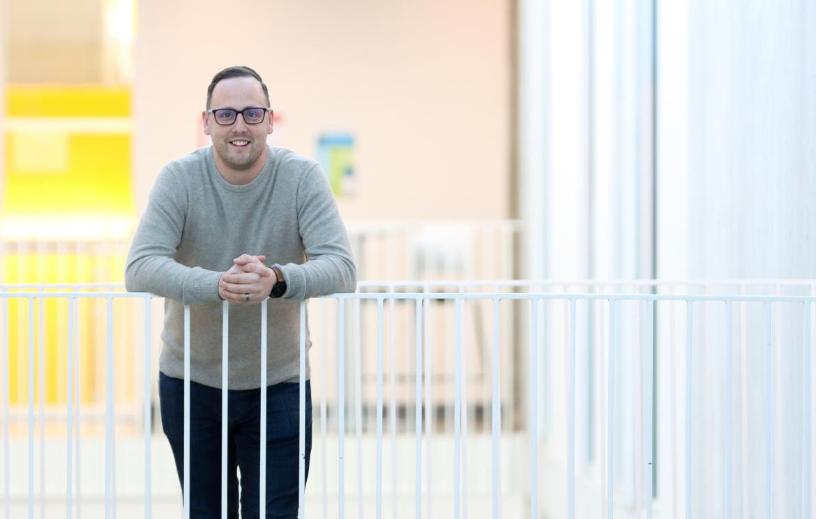 Dr. Kyle Duncan, a VIU Chemistry Professor,  smiles while leaning against a white railing.