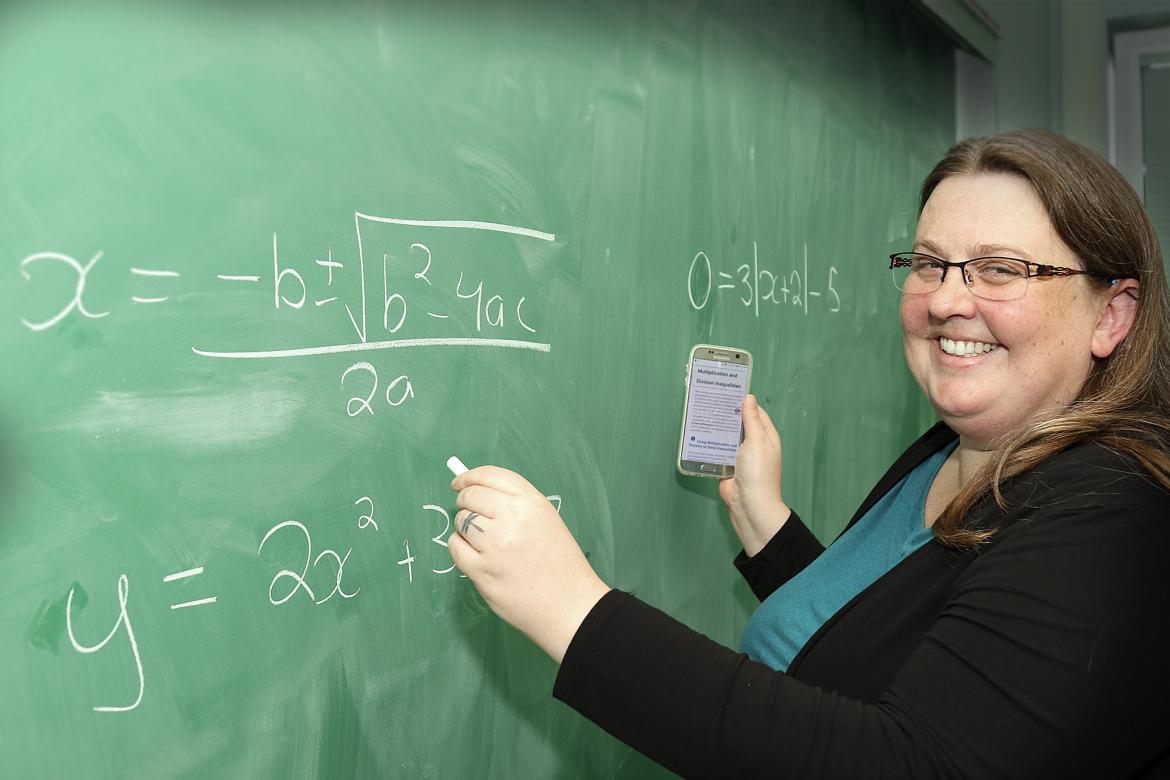 Lisa Lewis, VIUs acting chair of Adult Basic Education, draws math equations on a chalkboard while holding a cellphone