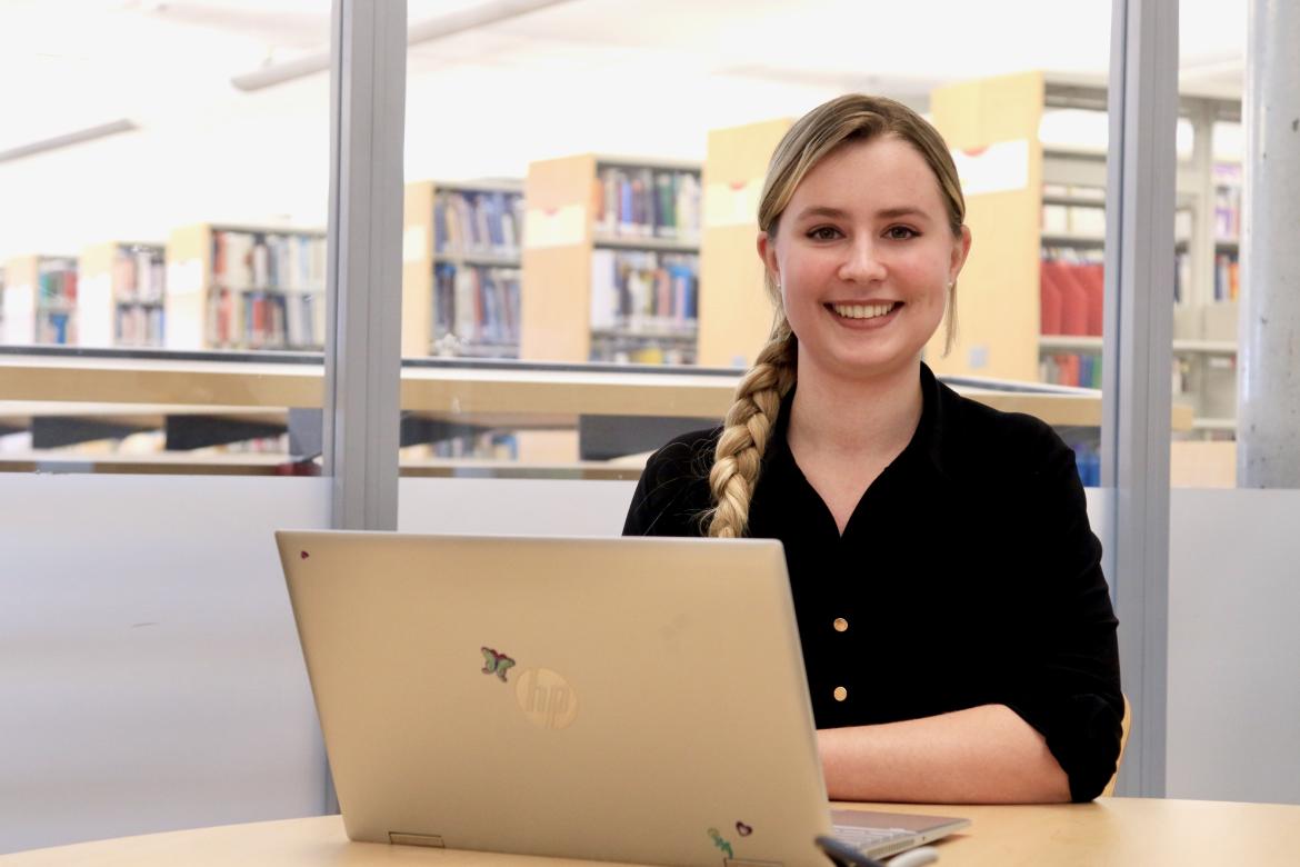 VIU Psychology student Cala Annala sitting at a desk with an open MacBook in front of her