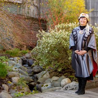Deborah Saucier wears her convocation regalia and poses in the gardens at VIU's Nanaimo campus