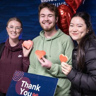 three students holding red heart cookies and a thank you sign