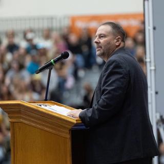 The president speaks at the podium in front of a packed gym