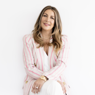 Jane Stoller sitting down against a white backdrop and smiling at the camera.