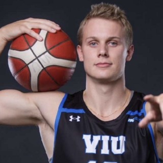 Kai Leighton in a Mariners jersey holding a basketball and pointing at the camera.