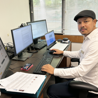 Dr. Ajay Shrestha sitting at his desk in front of multiple computer screens and looking at the camera.