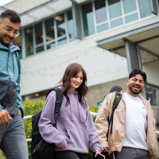 three students walking down the stairs in front of the VIU library.