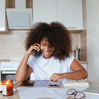 A woman looks at a tablet while sitting at a table