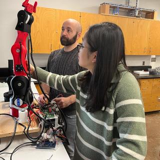 Dr. Xueling (Julie) Luo and Devin Ayotte adjust an 3D robotic arm.