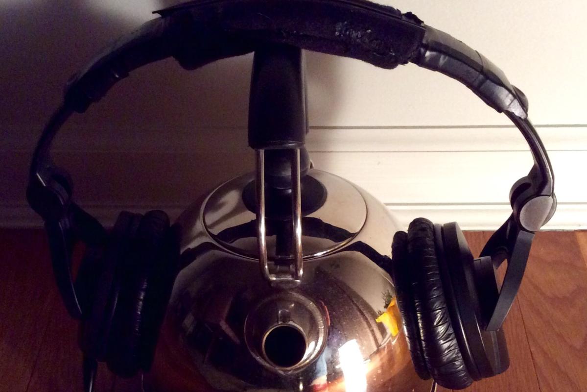 Headphones resting on a tea kettle.