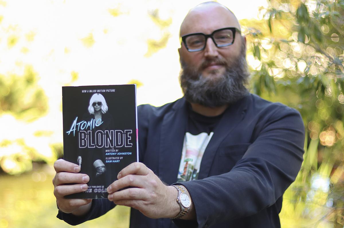 Theo Finigan holds out a copy of the book Atomic Blonde 