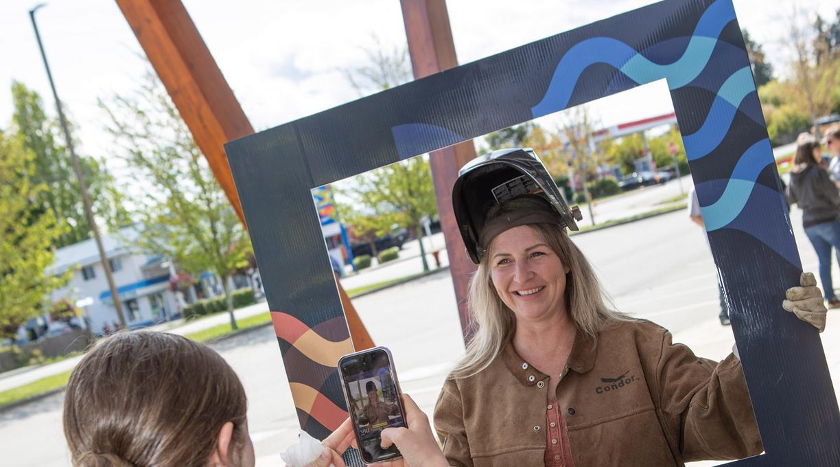 A student poses in a frame while another takes their photo