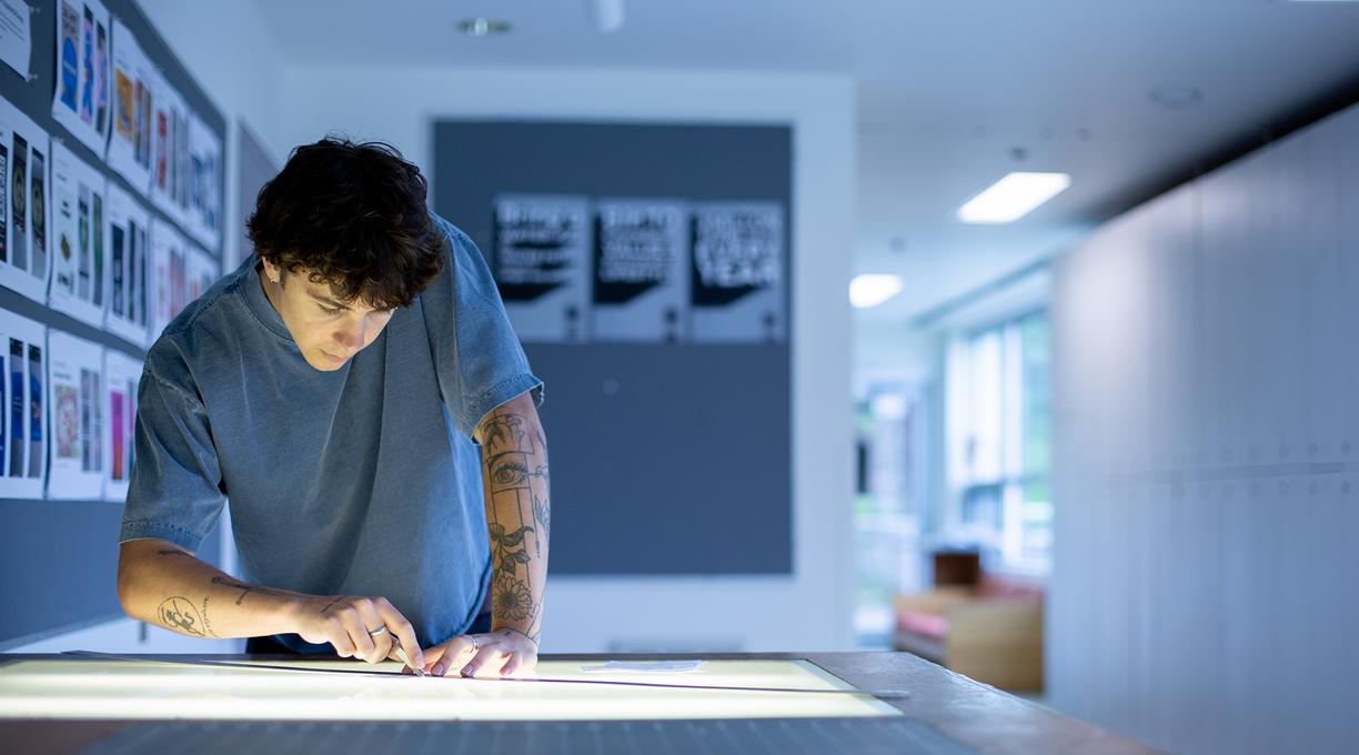 Ronin Carver works at a table in a graphic design classroom at VIU.