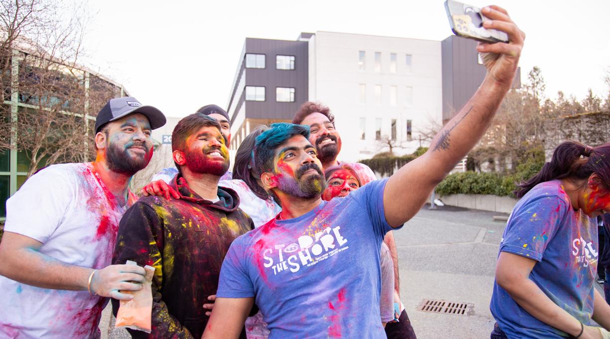 A group of students with coloured chalk on them pose for a selfie
