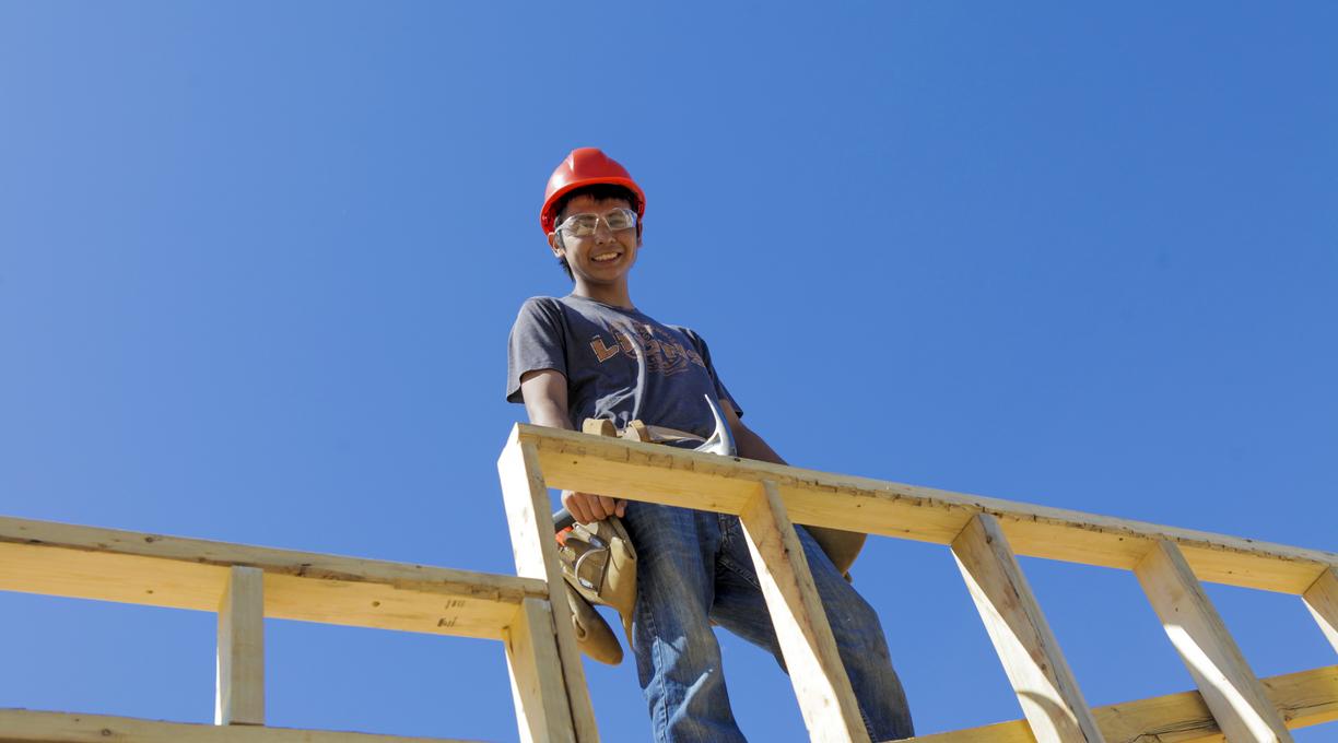 A carpenter up high building a frame