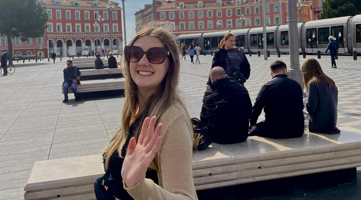 Jenna waves at the camera in a square