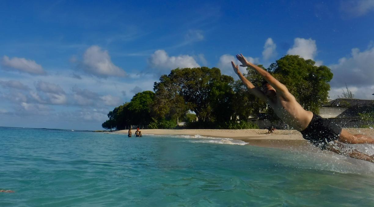 a person jumping into a very blue-green ocean