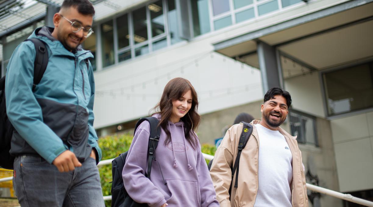 three students walking down the stairs in front of the VIU library.