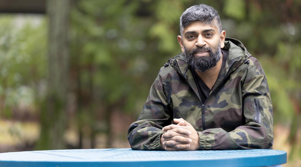Harold Chandra sits at a blue table outside